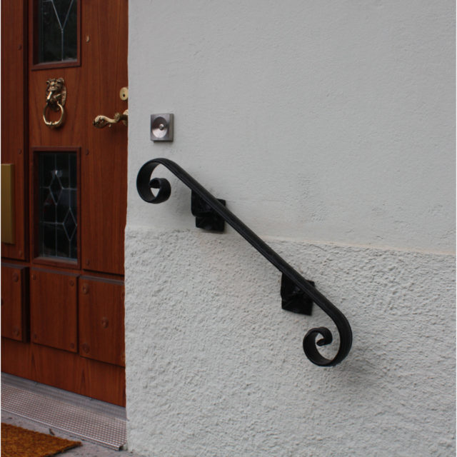 Musta käsijohde seinään. TAkorautainen käsijohde.