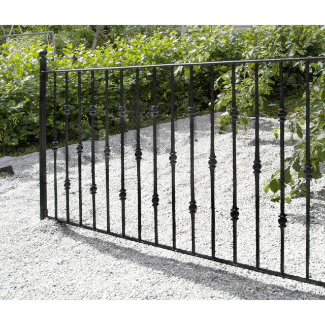 Tkorauta-aita tontin ympärille rajaamaan puutarhaa, musta metalliaita.